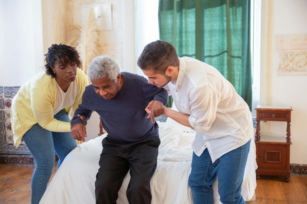 a man and a woman assisting an elderly man in standing. Photo by Kampus Production on Pexels.com